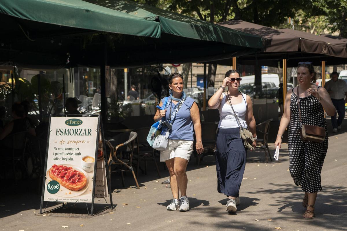 Tres mujeres pasando al lado de una cafetería Fornet en la Rambla de Catalunya. Barcelona, 17 de julio de 2026. Foto: Belén González / EP