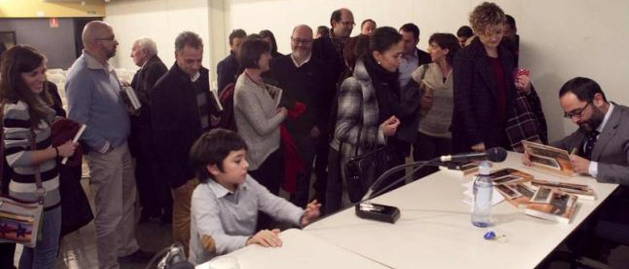 Eduardo Lagar firma autógrafos tras la presentación, en presencia de su hijo Mateo, en primer término a la izquierda. | miki lópez