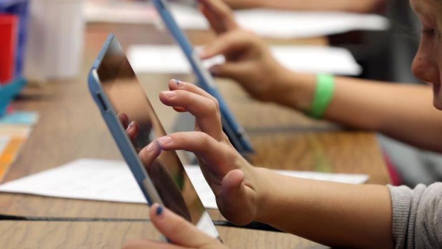 Una niña utiliza la tableta electrónica en clase.