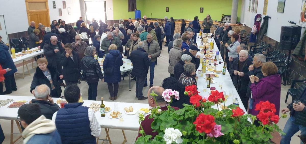 Sobre estas líneas, repartido de las macetas con geranios entre los vecinos de Venialbo con motivo de San Benito. Abajo, la imagen del santo durante la misa. | CEDIDA