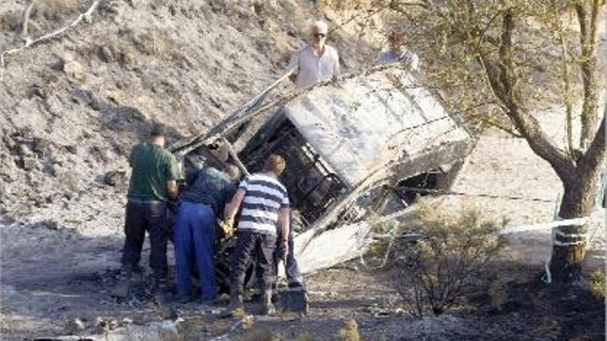 Diversos homes inspeccionen un vehicle totalment cremat a Alacant.