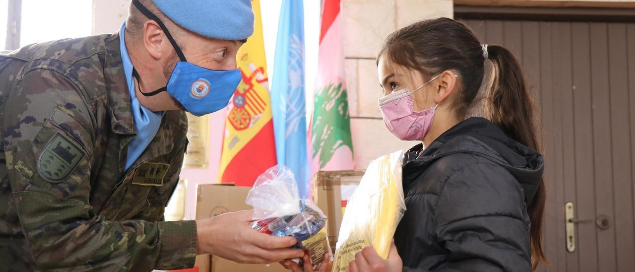 Un miembro de la Brigada Canarias XVI entrega material escolar a una niña libanesa