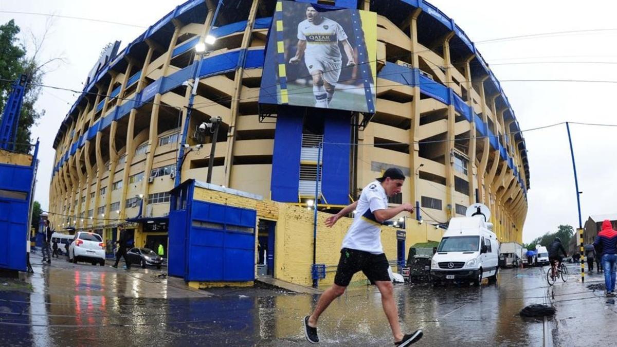 Un aficionado pasa por delante del estadio bajo la lluvia torrencial,