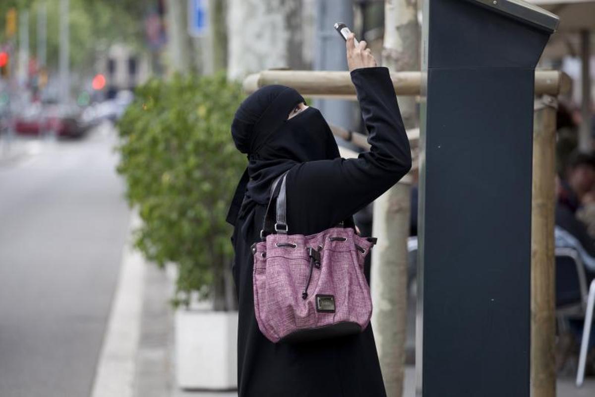 Una imagen de archivo de una mujer musulmana con burka niqab sacando fotos en el Paseo de Gràcia de Barcelona.