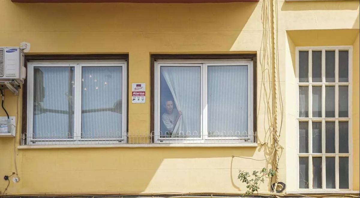 Una mujer asomada a la ventana de la casa del exministro de Transportes José Luis Ábalos durante un registro por parte de la UCO, a 10 de junio de 2025, en Valencia,