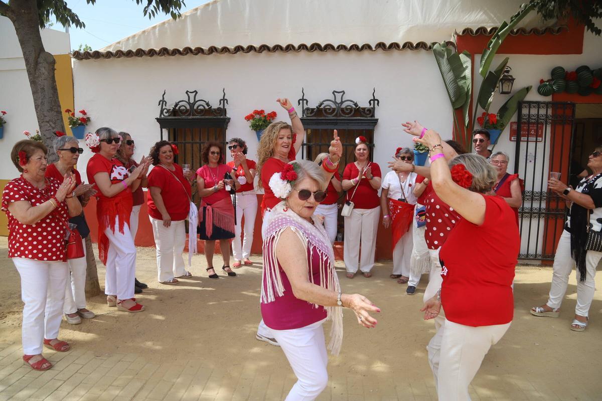 Un grupo de mujeres baila sevilla a las puertas de una caseta este lunes de Feria.