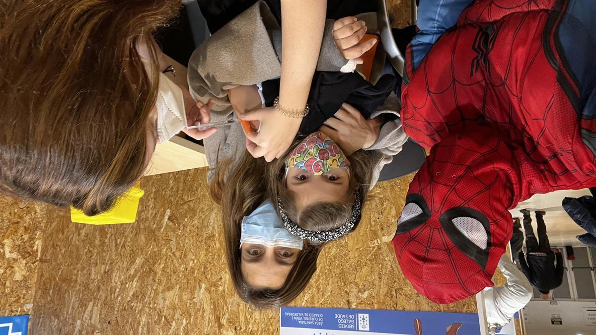 Spiderman acompañando a una niña mientras recibe la vacuna pediátrica, ayer en Expourense.