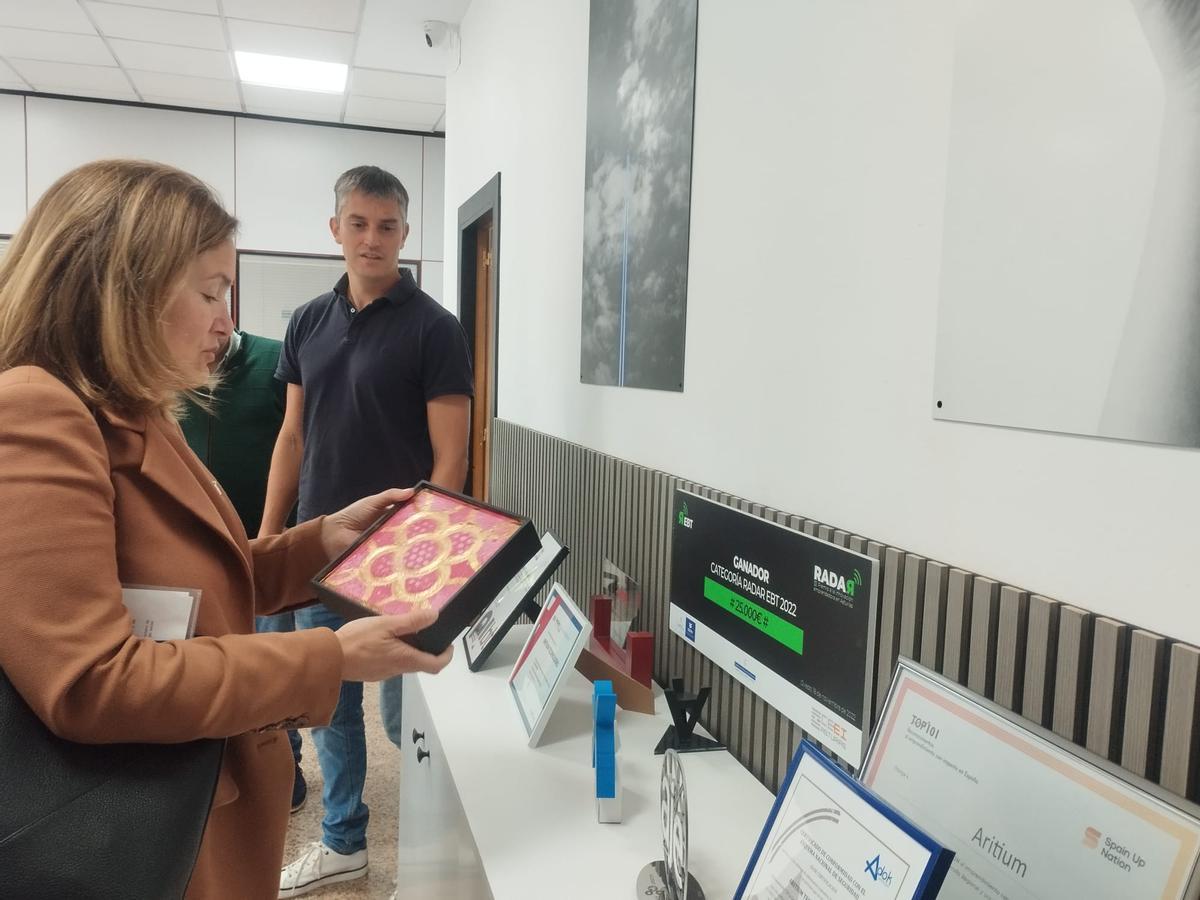 La directora general de Desarrollo Rural, Begoña López, observa los premios que ha recibido la empresa, con el CEO, Ángel Colado, al fondo.