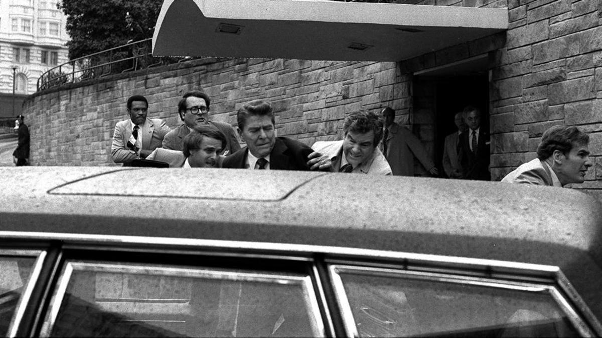 Reagan es introducido por sus escoltas en el coche presidencial tras los disparos de Hinckley.