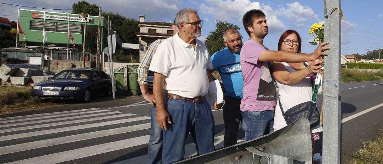 La pareja de la joven, en la imagen apoyado en la señal, dejó flores en el lugar del accidente. // R. Grobas