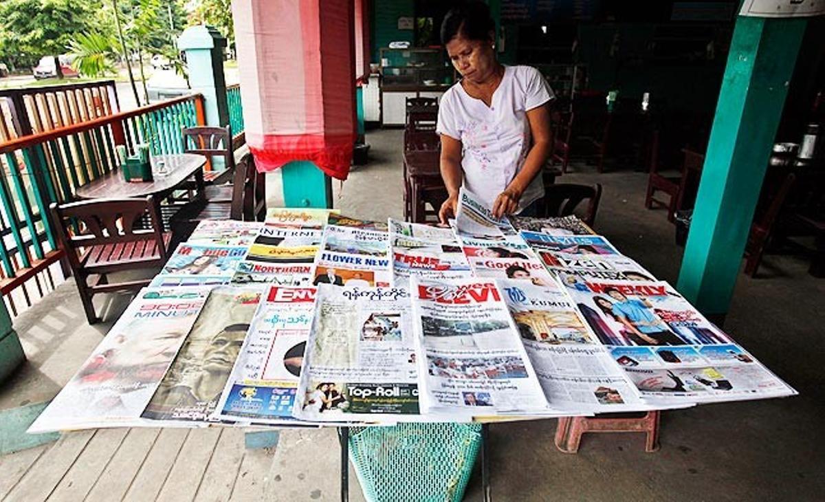 Una venedora col·loca uns diaris en una botiga de Rangun (Birmània) aquest dijous. El Govern birmà ha aprovat una nova llei de censura que evitarà que més d’un centenar de publicacions s’hagin de sotmetre a la inspecció de la comissió de censura.