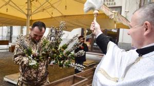 Un soldado ucraniano recibe el agua sagrada en la ceremonia de consagración de las ramas de sauce del Domingo de Pascua, en la ciudad ucraniana de Leópolis.