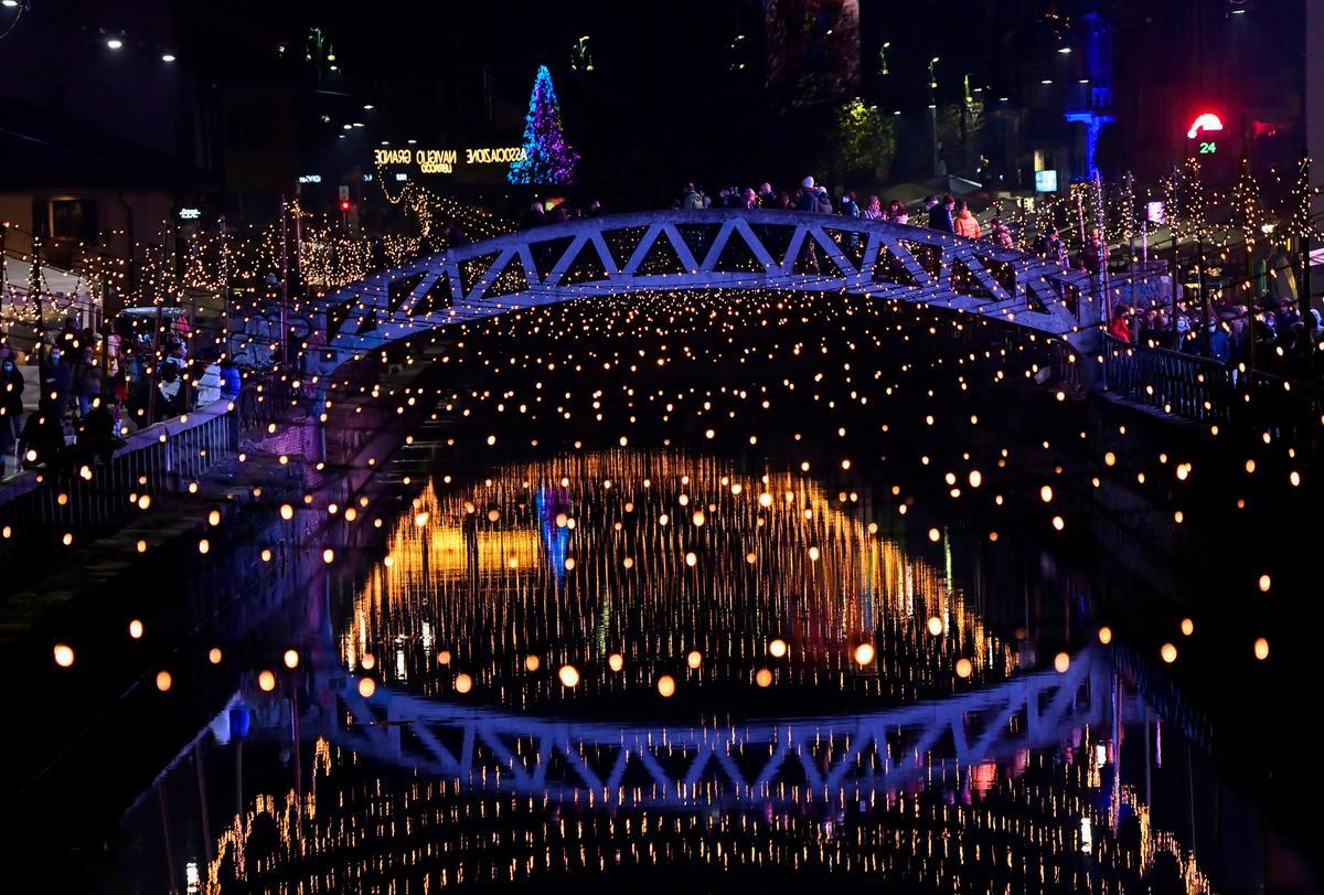 El espíritu navideño llega a Milán, la gente camina sobre un puente del canal Naviglio Grande.