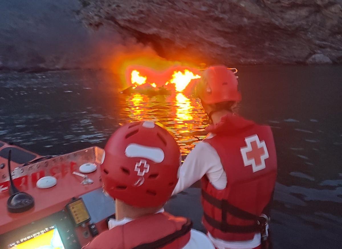 Miembros de Cruz Roja en una embarcación, aproximándose al barco en llamas.