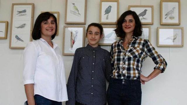 Isabel González, Olaya Ramiro y Rosa González, delante de su exposición de aves, en la biblioteca de Lugo.