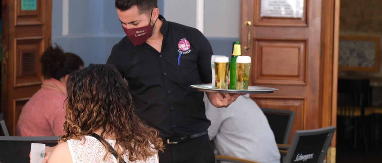 Un camarero sirve una cerveza en una terraza de un bar de la capital grancanaria.