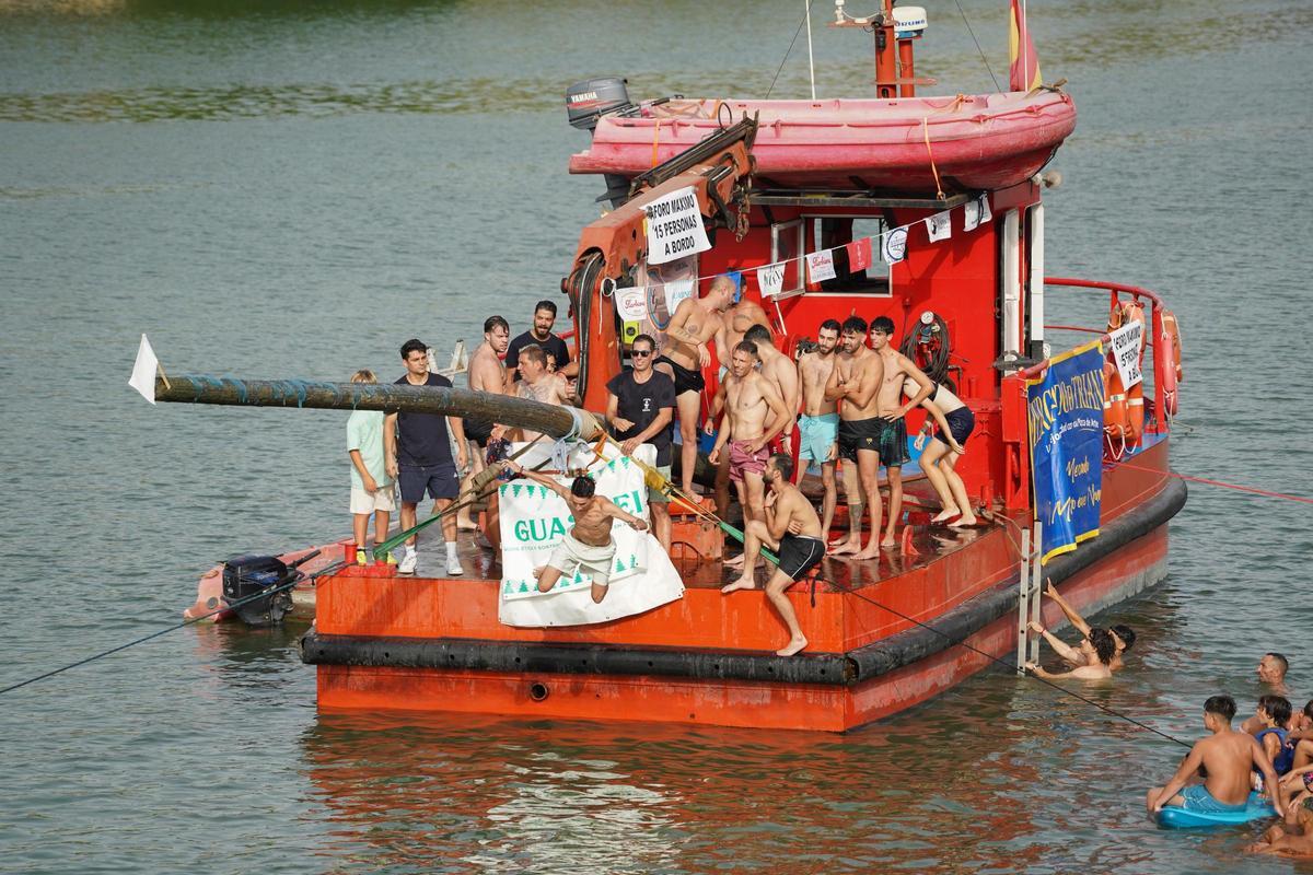 La 'cucaña', el juego centenario que regresa cada verano al río Guadalquivir por la Velá de Santa Ana en imágenes