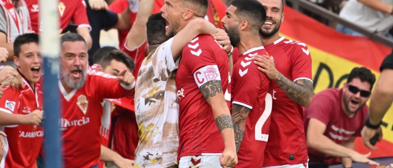 Andrés Carrasco y sus compañeros celebran el gol con los miles de aficionados granas que seguían el choque en uno de los fondos del Rico Pérez. | PRENSA REAL MURCIA