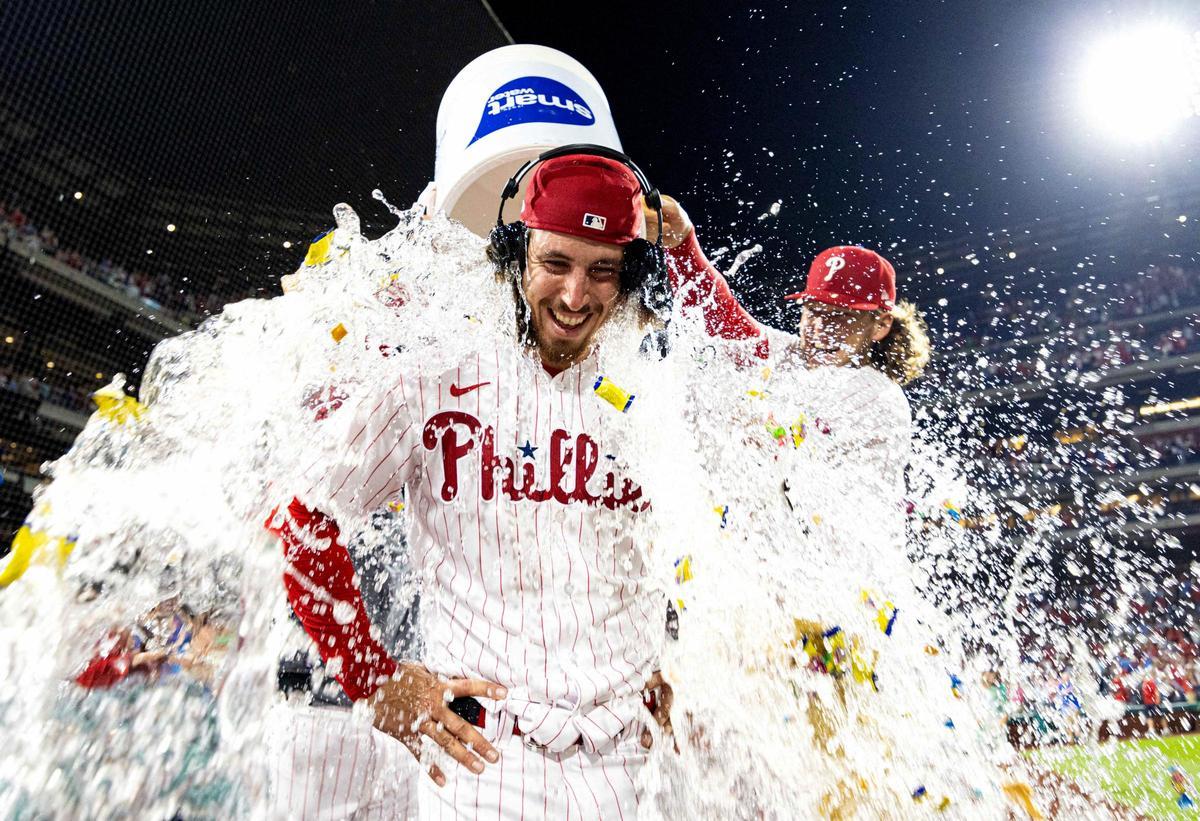 El lanzador de los Filis de Filadelfia, Michael Lorenzen, es rociado con agua por el primer base Alec Bohm.