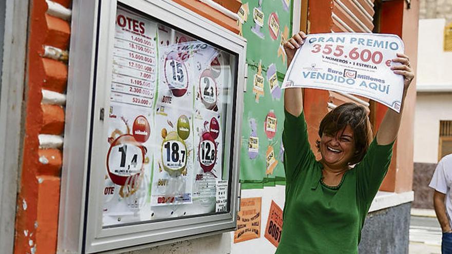 La lotera Ruth Almeida sostiene el cartel que acredita el premio.