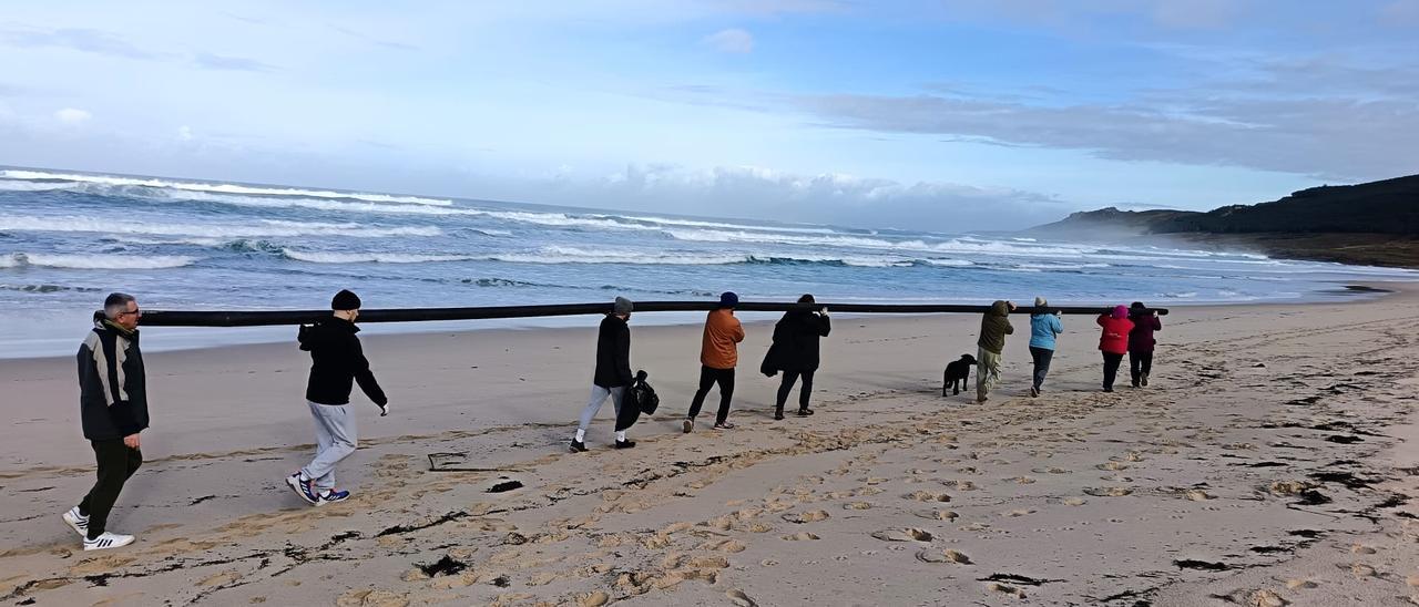 Voluntarios retirando un tubo plástico de 18 metros da praia de Traba.