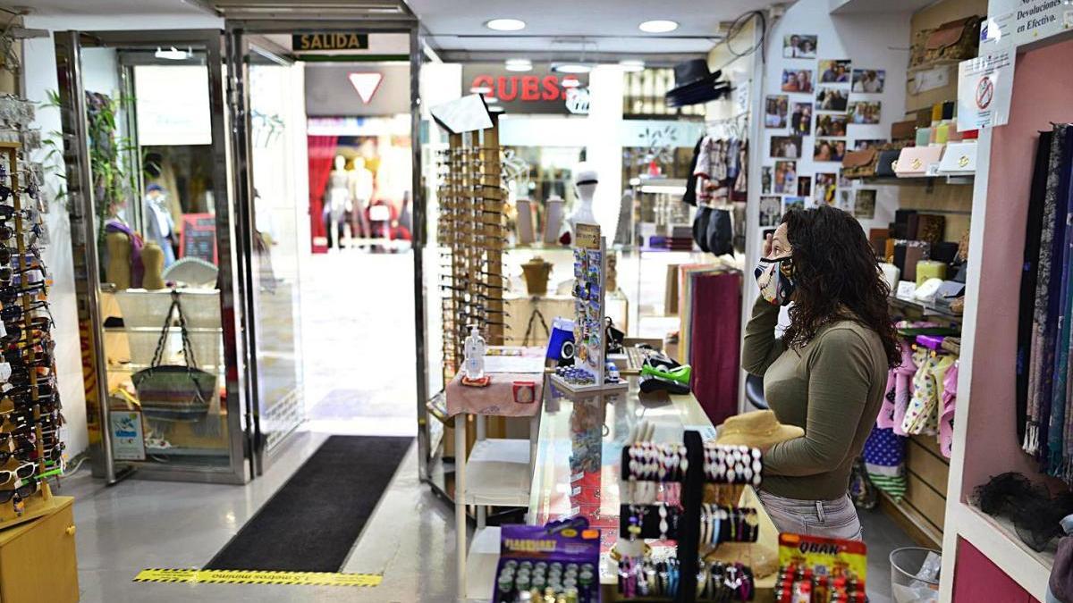 Una dependienta vigila la puerta del negocio a la espera de clientes.