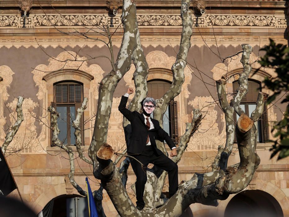 Un manifestante con la máscara de Puigdemont se sube a un árbol durante la protesta de esta tarde en Barcelona.