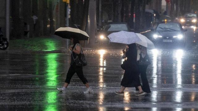 Diverses persones passegen per Barcelona durant un dia de pluja.