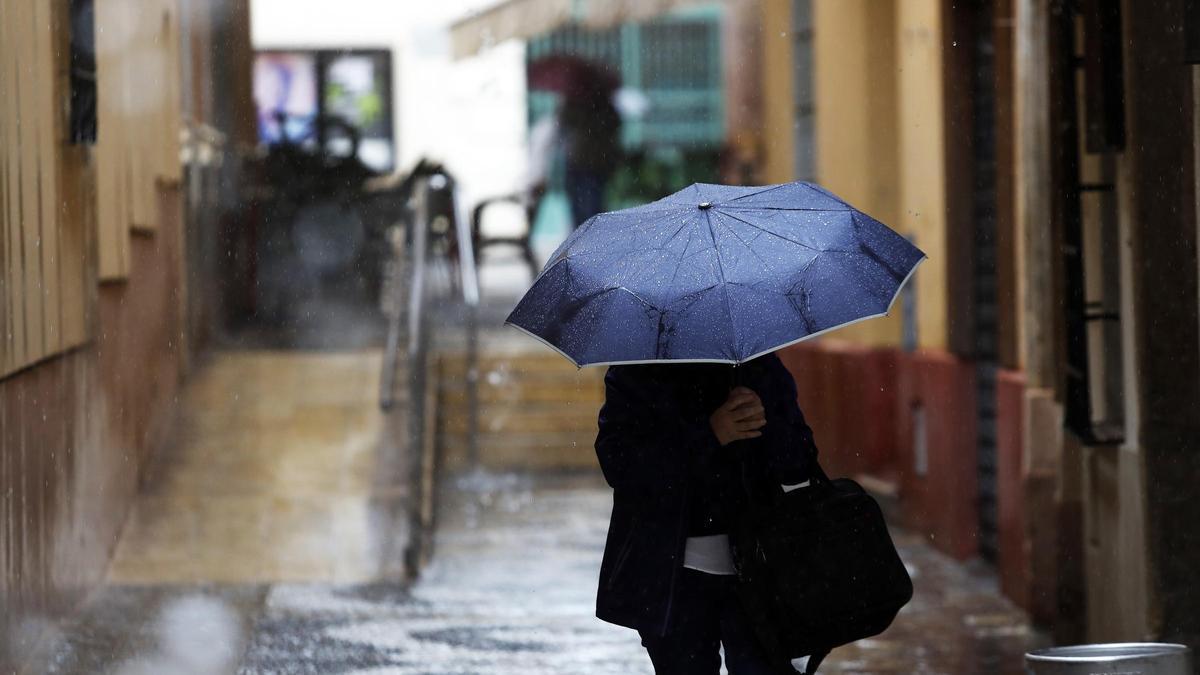Una persona se protege de la lluvia en Málaga