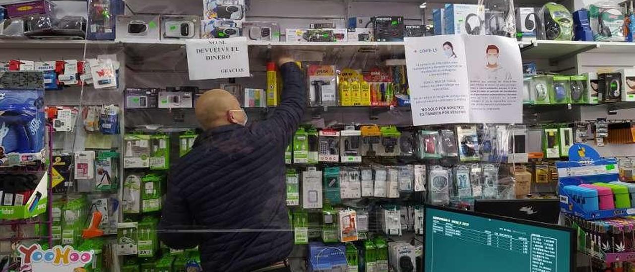 Un plástico separa al vendedor -con mascarilla- del cliente en la caja de este bazar oriental. // AC