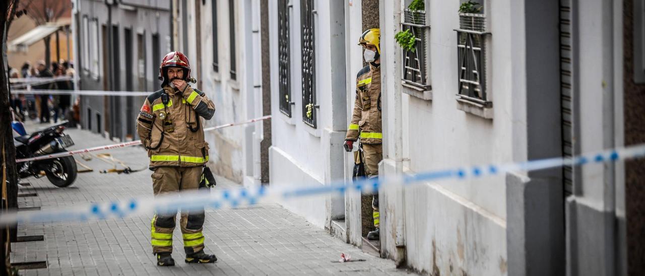 Dos bomberos en la portería del número 9 de la calle Canigó, el día del derrumbe