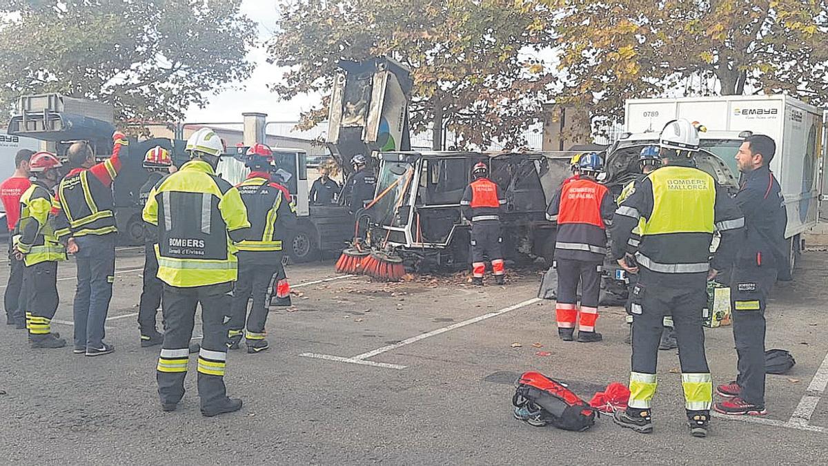 Los bomberos que participan en el cursillo, frente a una de las máquinas barredoras incendiadas.