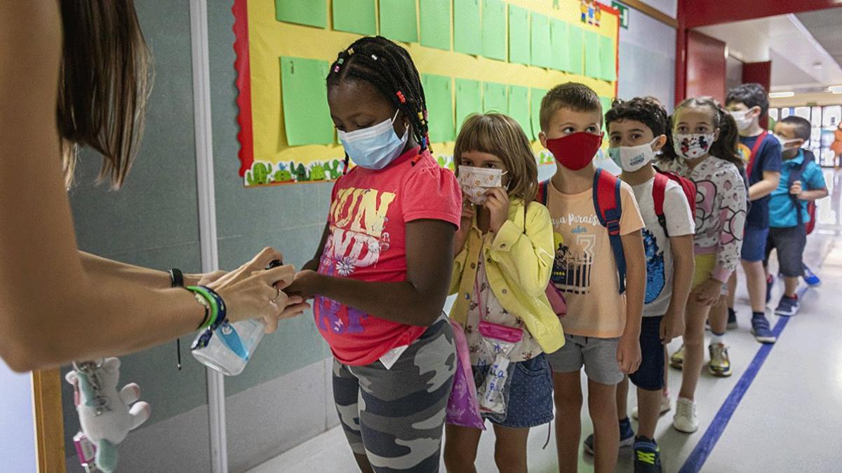 Un grupo de niños hacen cola para desinfectarse las manos antes de entrar en clase, en un colegio de Benimaclet (València), este lunes 7 de septiembre