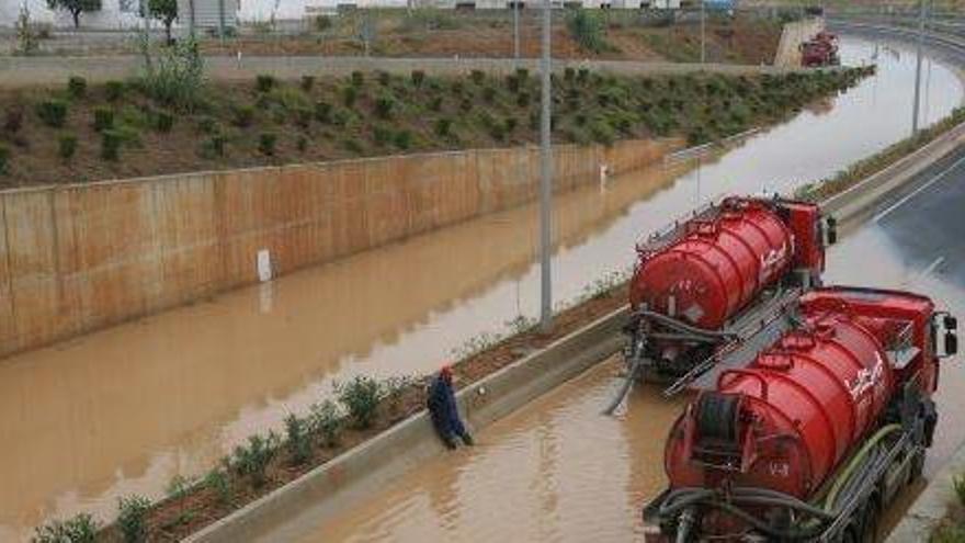 Dos camiones tratan de retirar el agua que inunda la autovía del aeropuerto, en una imagen de archivo.