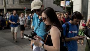Uns turistes russos consulten la seva aplicació mòbil, al setembre.
