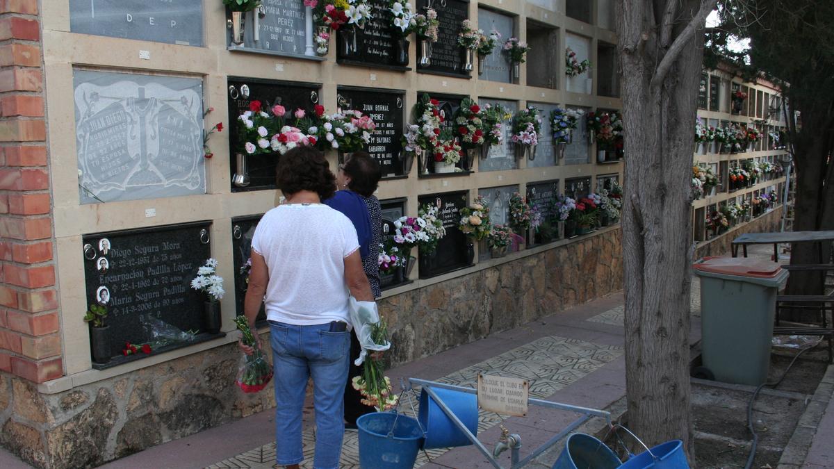 Dos mujeres ponían flores en un nicho en el cementerio de San Clemente en Lorca.