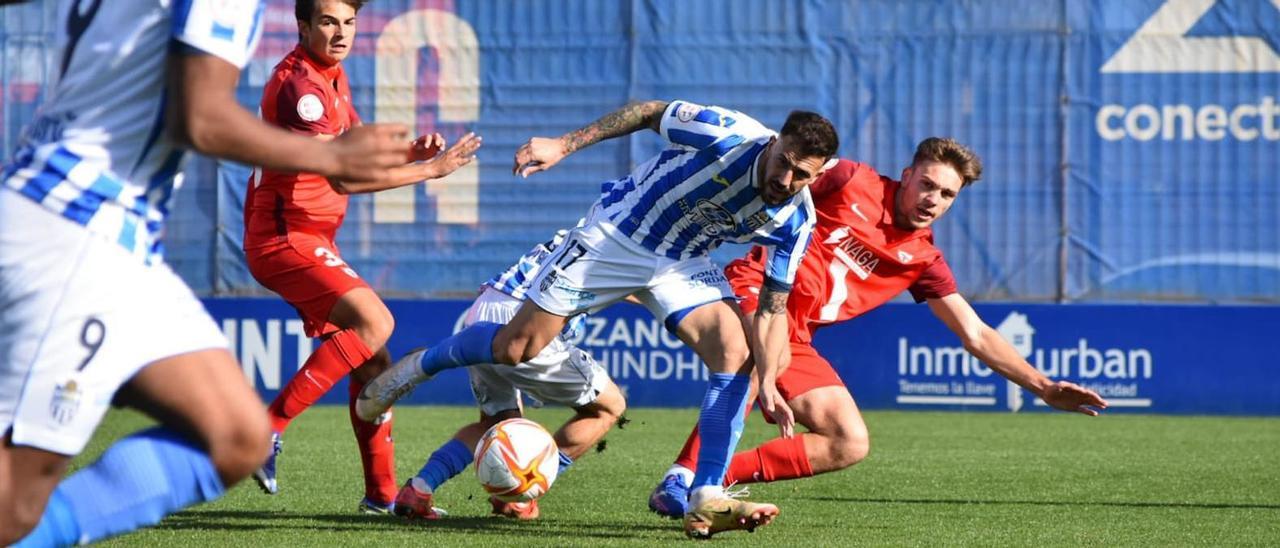 Dioni intentan llevarse la pelota ante un defensa sevillista.