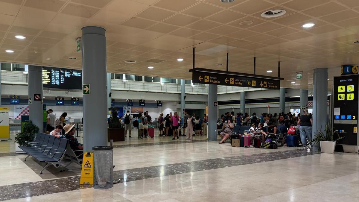 Una cola de gente espera para recibir atención en el mostrador de Volotea, en el aeropuerto de Asturias.