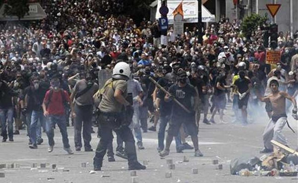 Un agent suporta una pluja de llambordes durant la multitudinària manifestació davant de l’edifici del Parlament a Atenes.