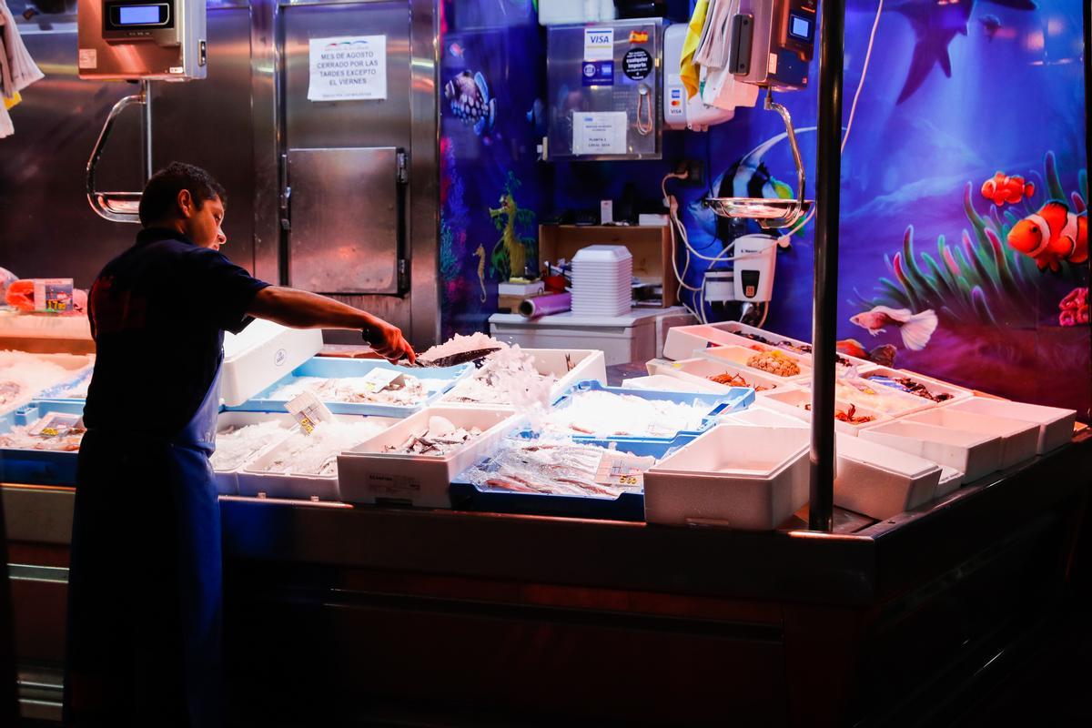 Un trabajador echa hielo a los productos de una pescadería en Madrid.