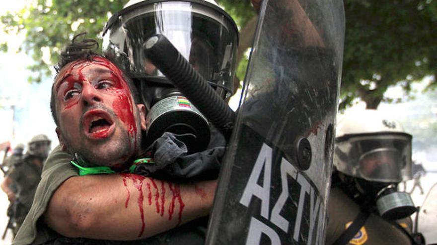 Un policia actua contundentment contra un manifestant que sagna de manera abundant a Atenes.