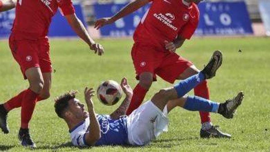 Varios futbolistas de la UD Ibiza presionan a un rival caído en el suelo.
