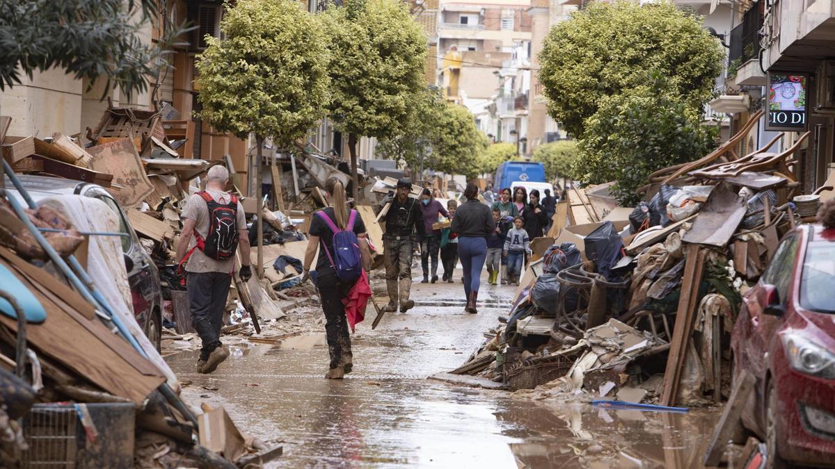 Una calle llena de barro y enseres apilados tras la dana del 29 de octubre de 2024.