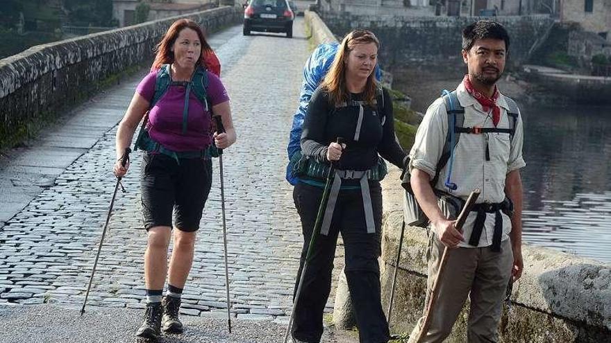 Peregrinos a su paso por el puente medieval de Pontesampaio. // R. V.