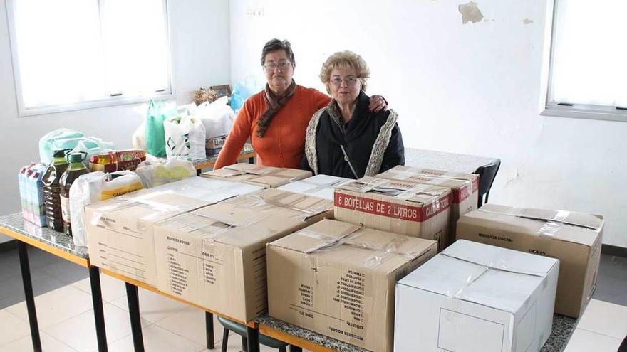 Marisol González (izquierda) y Lourdes Cueto posan con los alimentos en el centro social de Hevia.