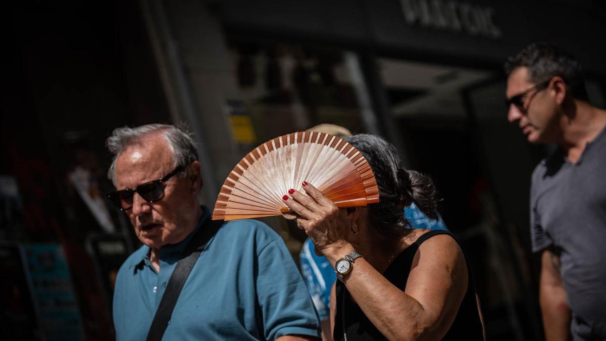 Una mujer se cubre con el abanico.