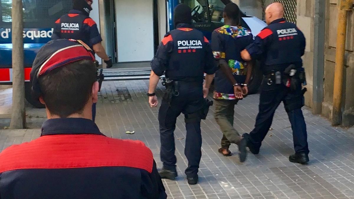 Agentes de los Mossos se llevan a uno de los detenidos en la operación contra el 'top manta' en Barcelona