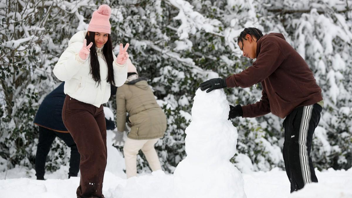 Una pareja de jóvenes hace un muñeco de nieve en Pedrafita