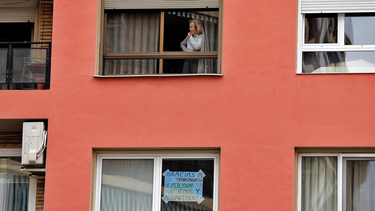 Una mujer observa la calle desde la ventana de una vivienda de Valencia durante el confinamiento.