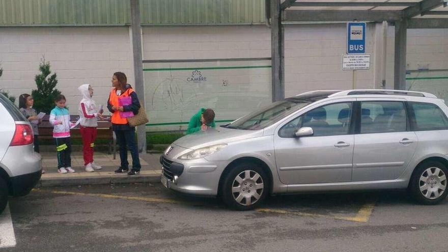 Un escolar multa a un coche aparcado en una parada de bus, junto al colegio O Graxal.